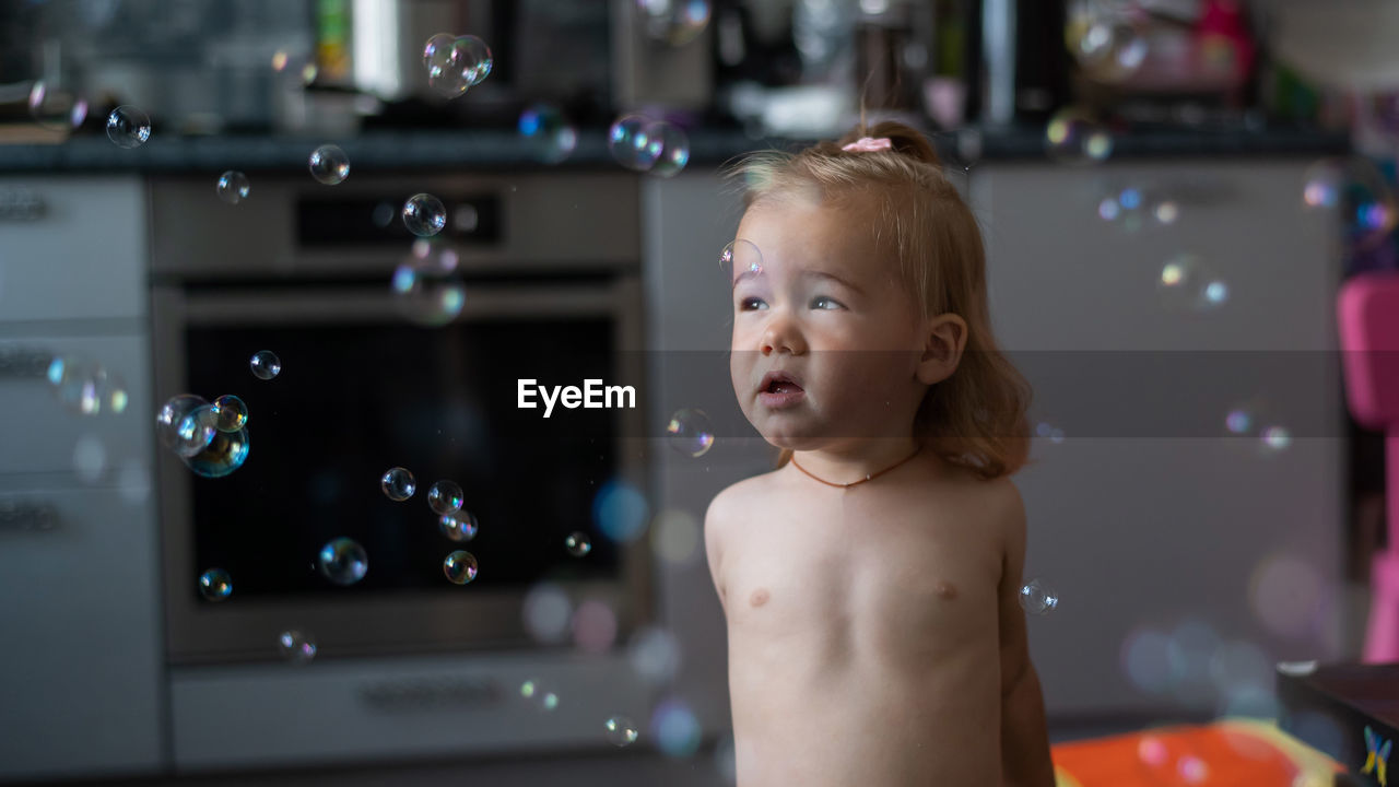 Portrait of shirtless boy looking at bubbles