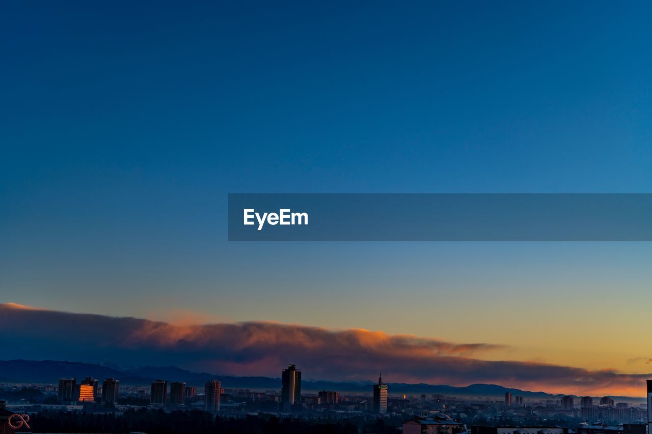 Scenic view of city against clear sky at sunset