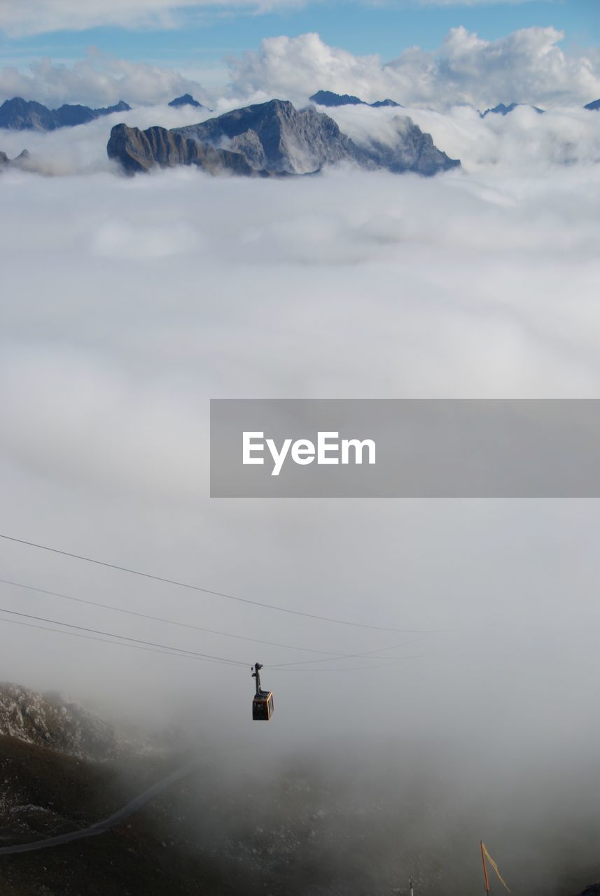 Overhead cable car over clouds and mountains