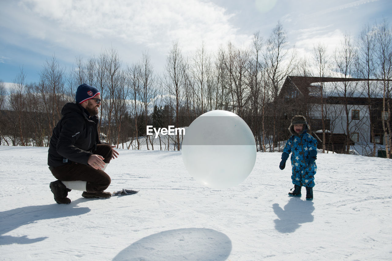 Father and son playing with ball in snow in winter on sunny day