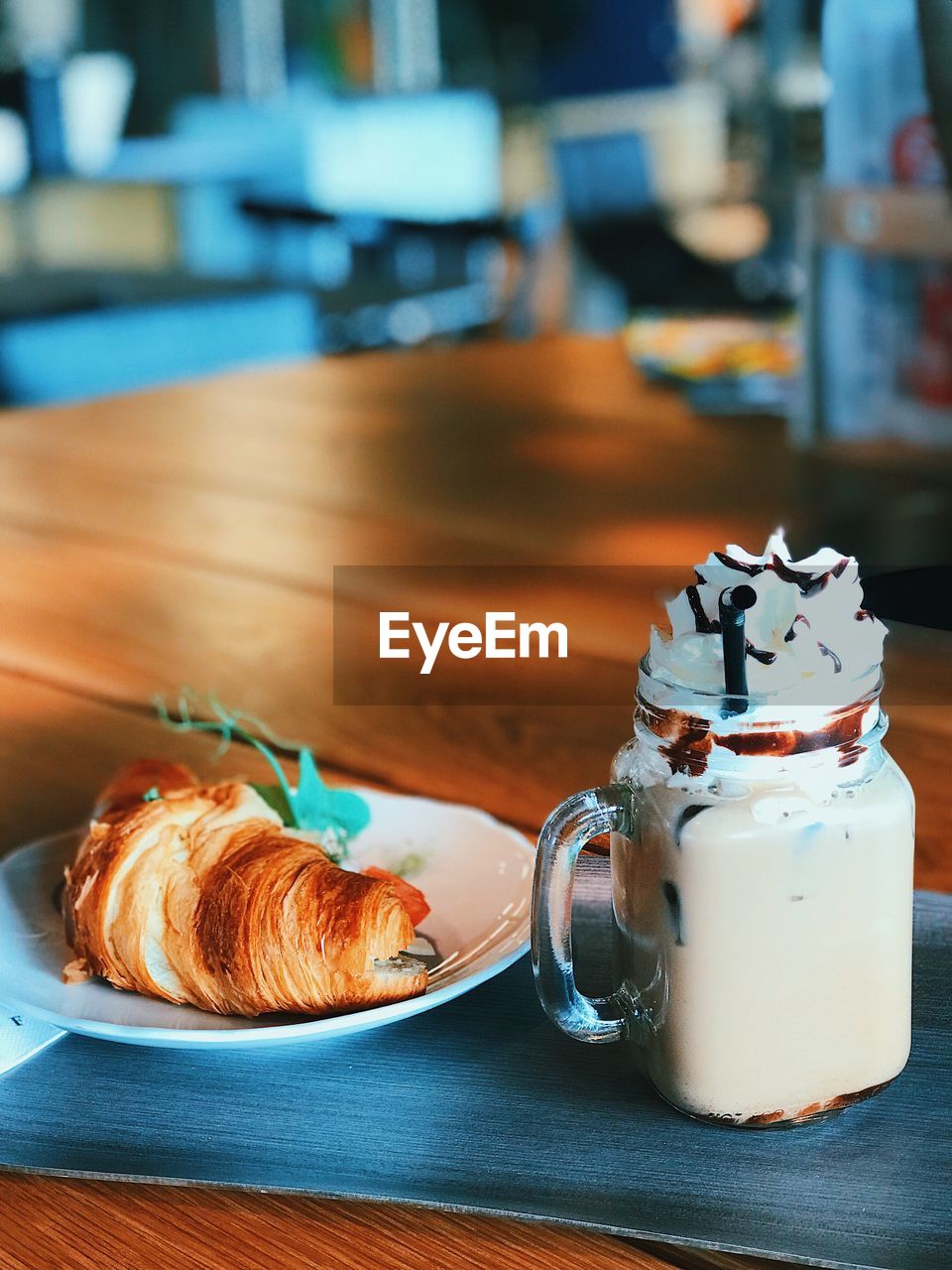 Close-up of croissant with iced coffee served on table in restaurant