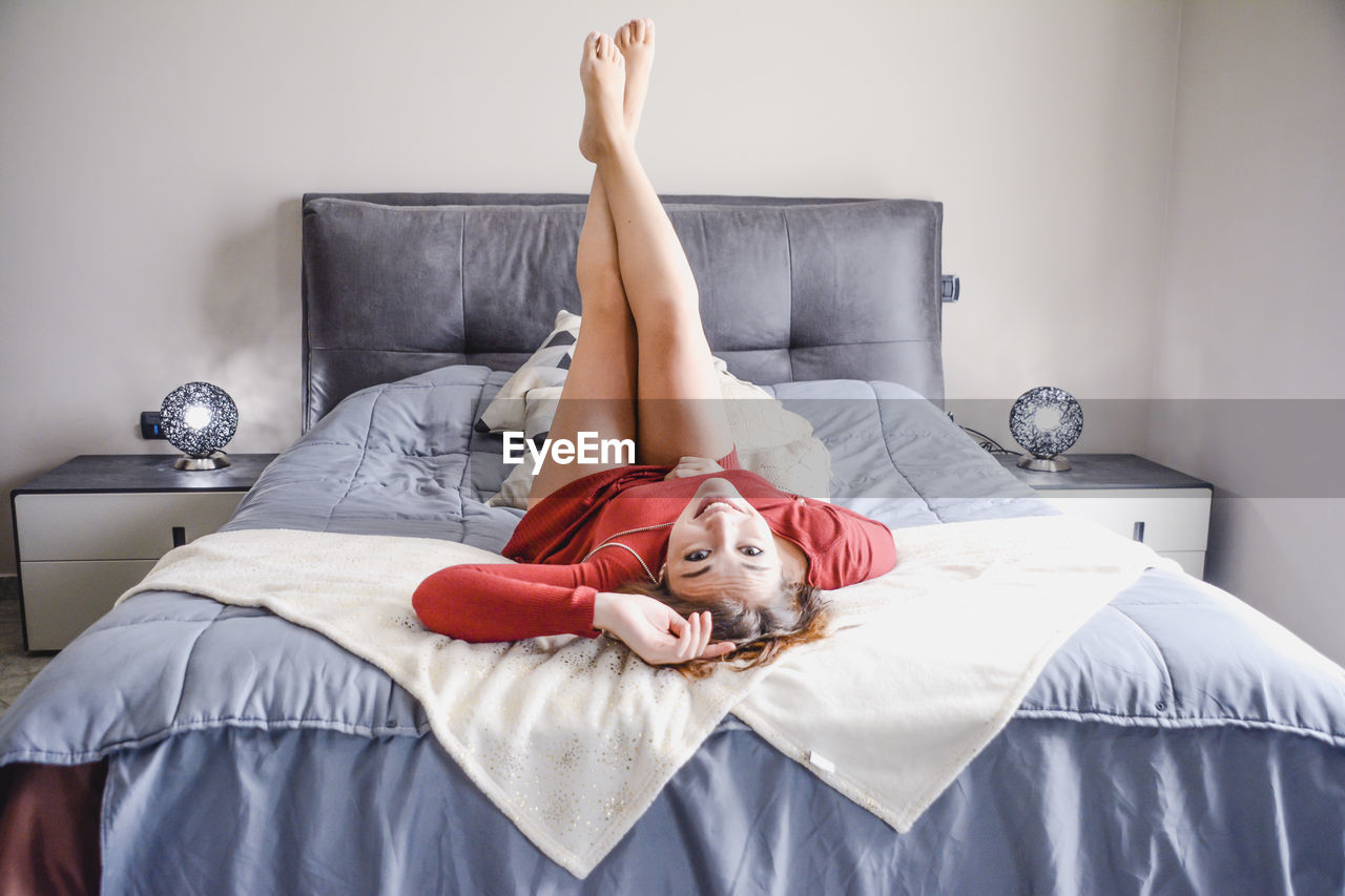 Portrait of woman lying on bed at home