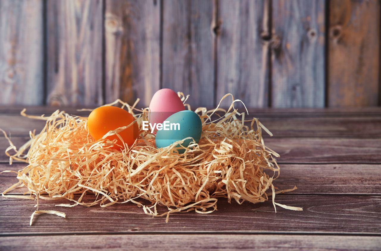 Easter eggs in straw on wooden background