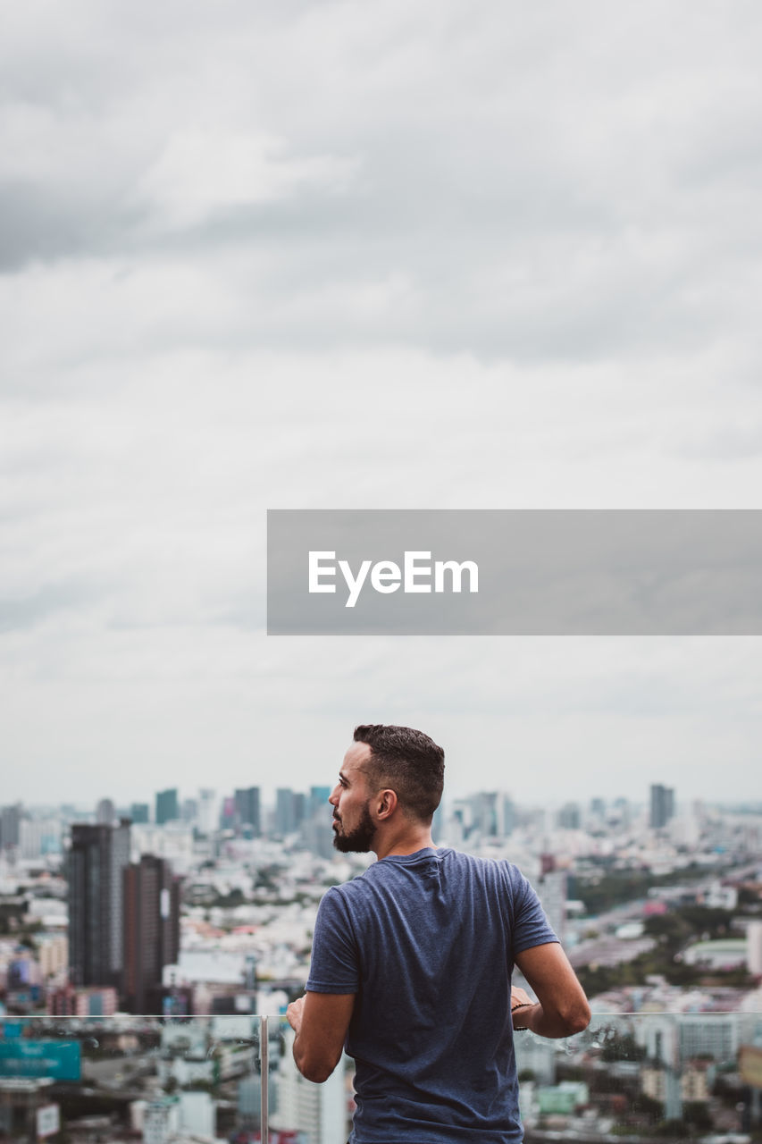 YOUNG MAN LOOKING AT CITYSCAPE