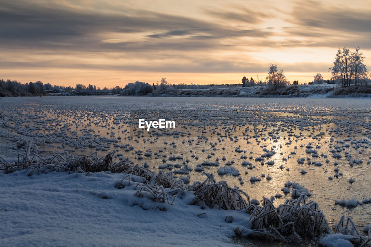 Scenic view of snow covered field against sky during sunset