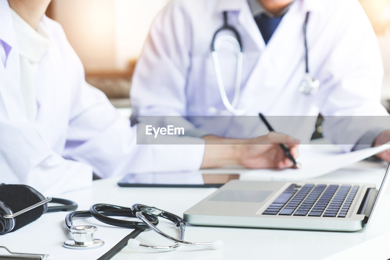 Midsection of doctors working on table at hospital