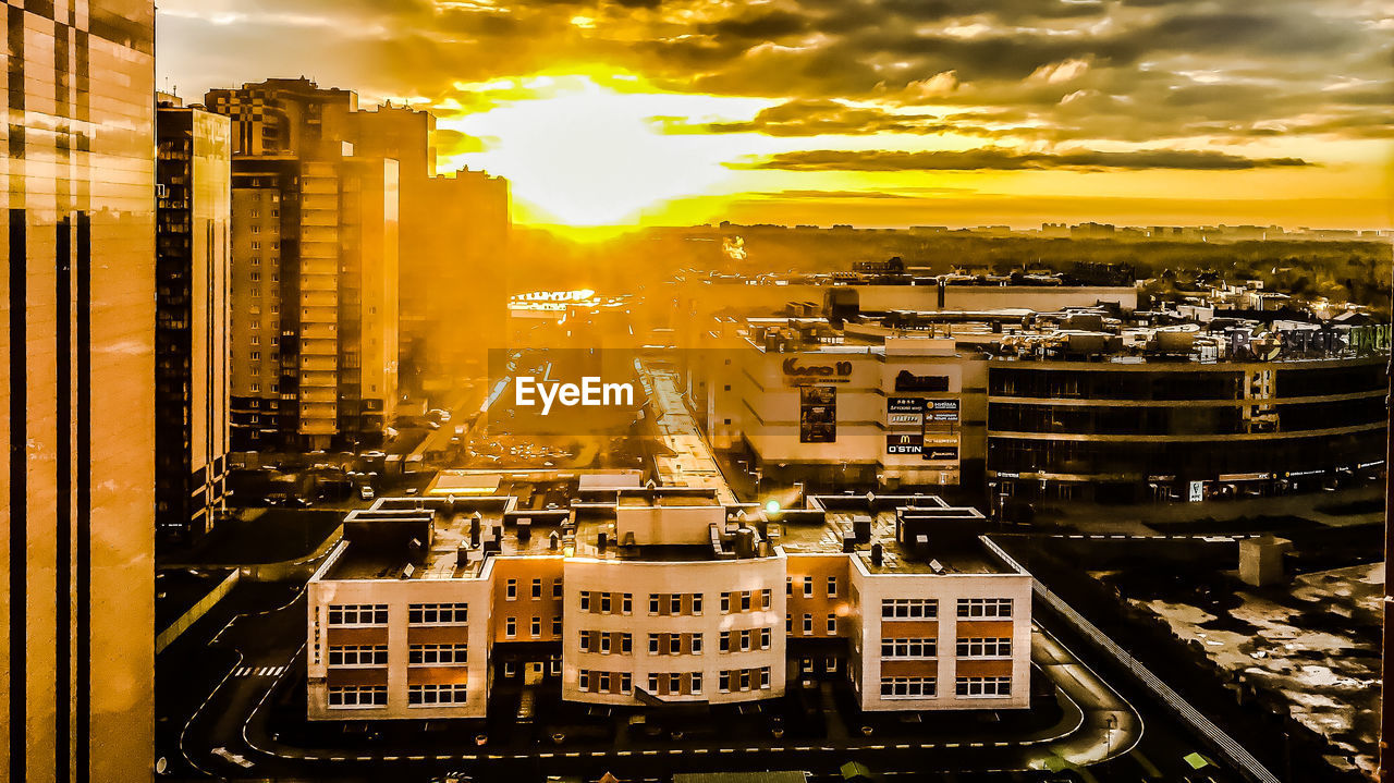 HIGH ANGLE VIEW OF CITY BUILDINGS AGAINST SKY DURING SUNSET