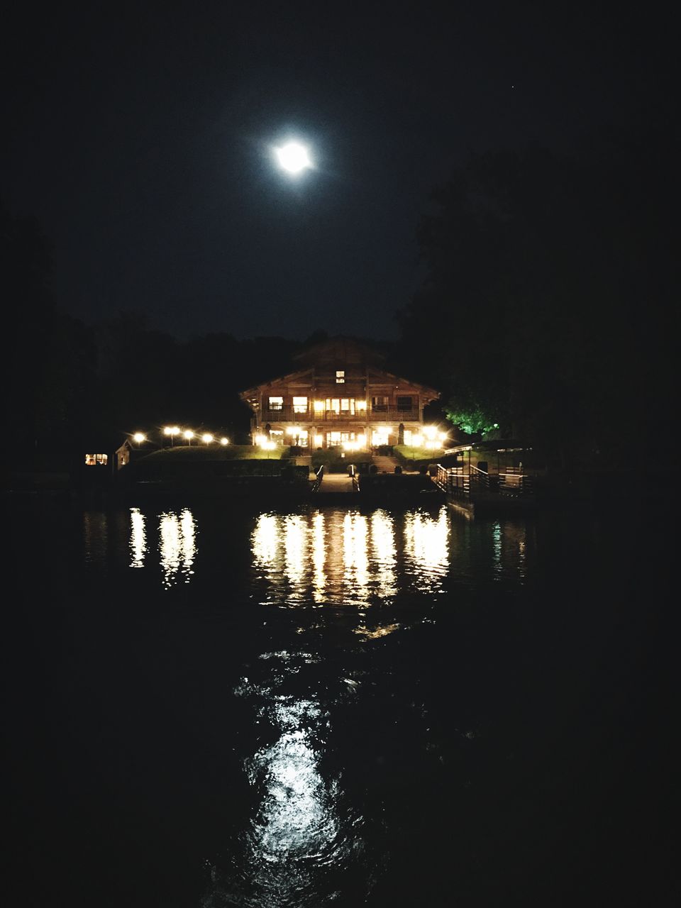 ILLUMINATED BUILT STRUCTURES BY RIVER AGAINST SKY