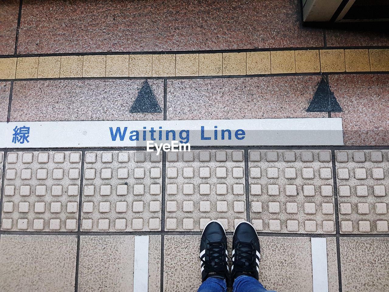 LOW SECTION VIEW OF PERSON STANDING ON SIGN