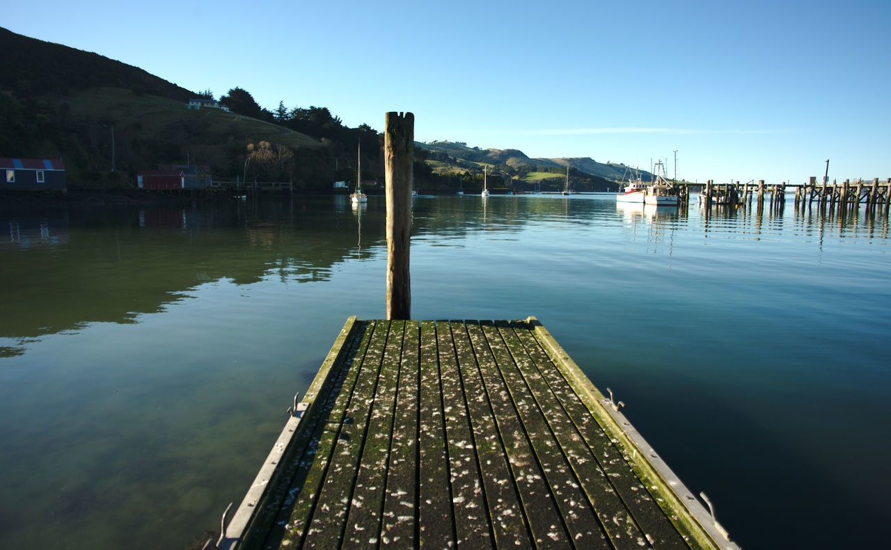 Wooden posts in lake against clear sky