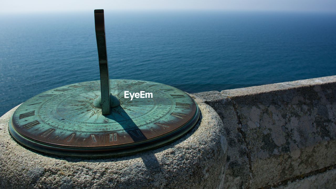 Sundial by retaining wall at seaside