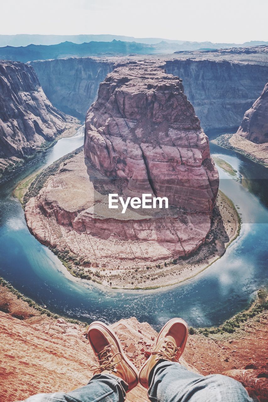 Low section of man sitting against horseshoe bend