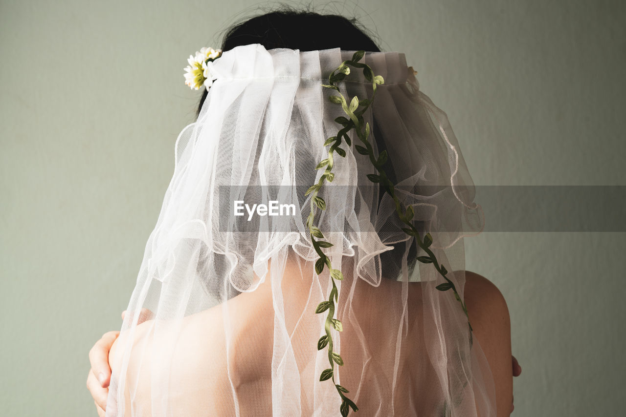 Rear view of bride with veil against wall