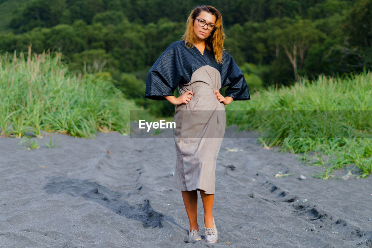 Portrait of mid adult woman standing at beach against trees