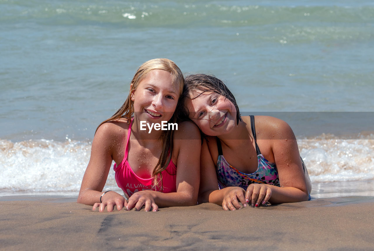 Two young girls show they are the best of friends, as they pose on a beach off of lake michigan usa