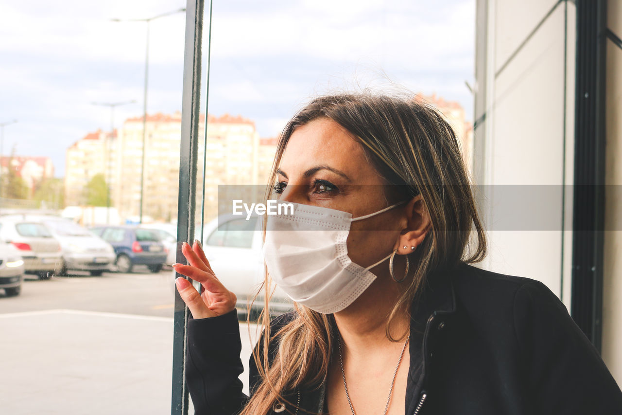 A woman with a mask looking through the window