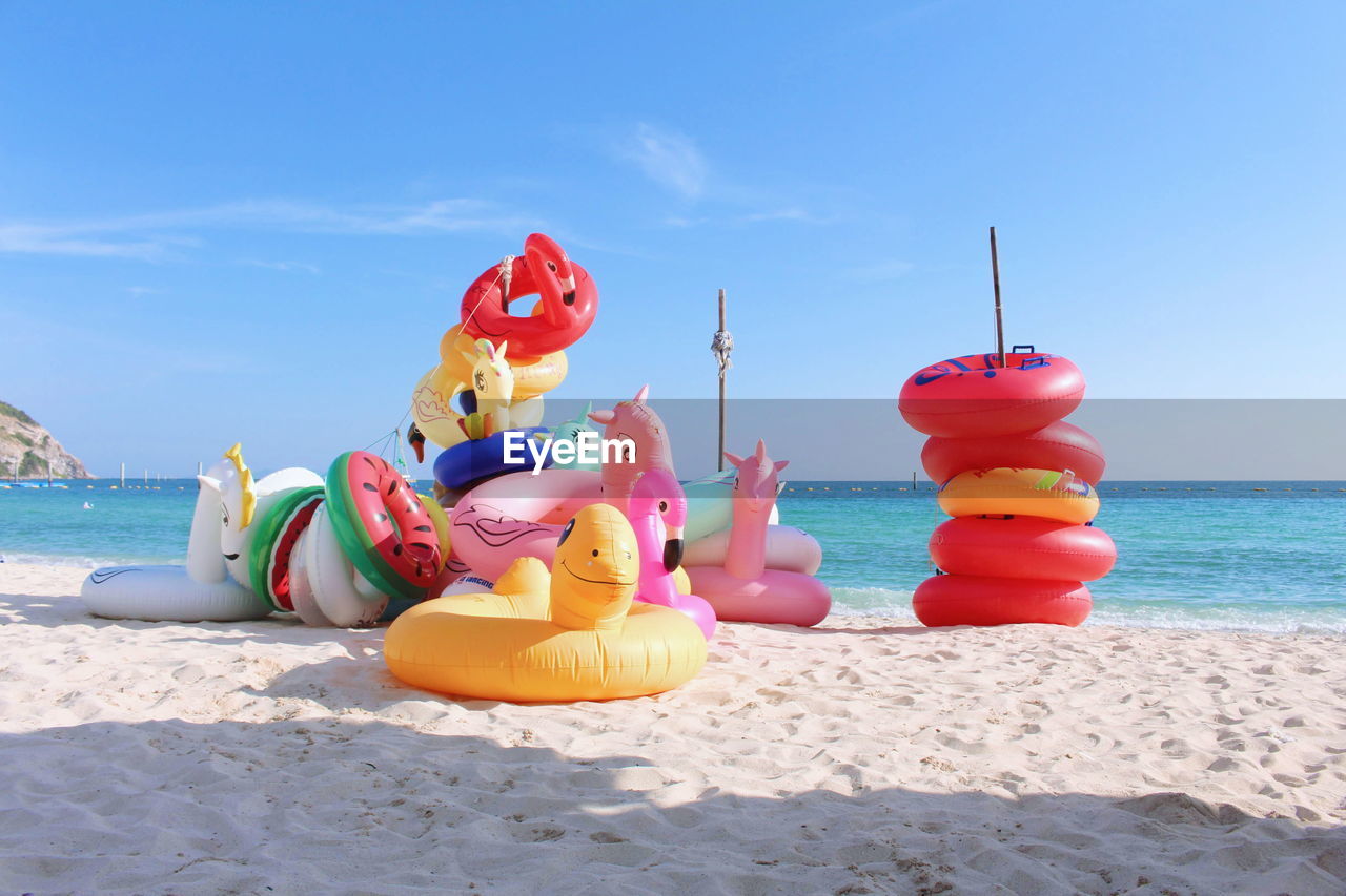 Multi colored toys on beach against sky