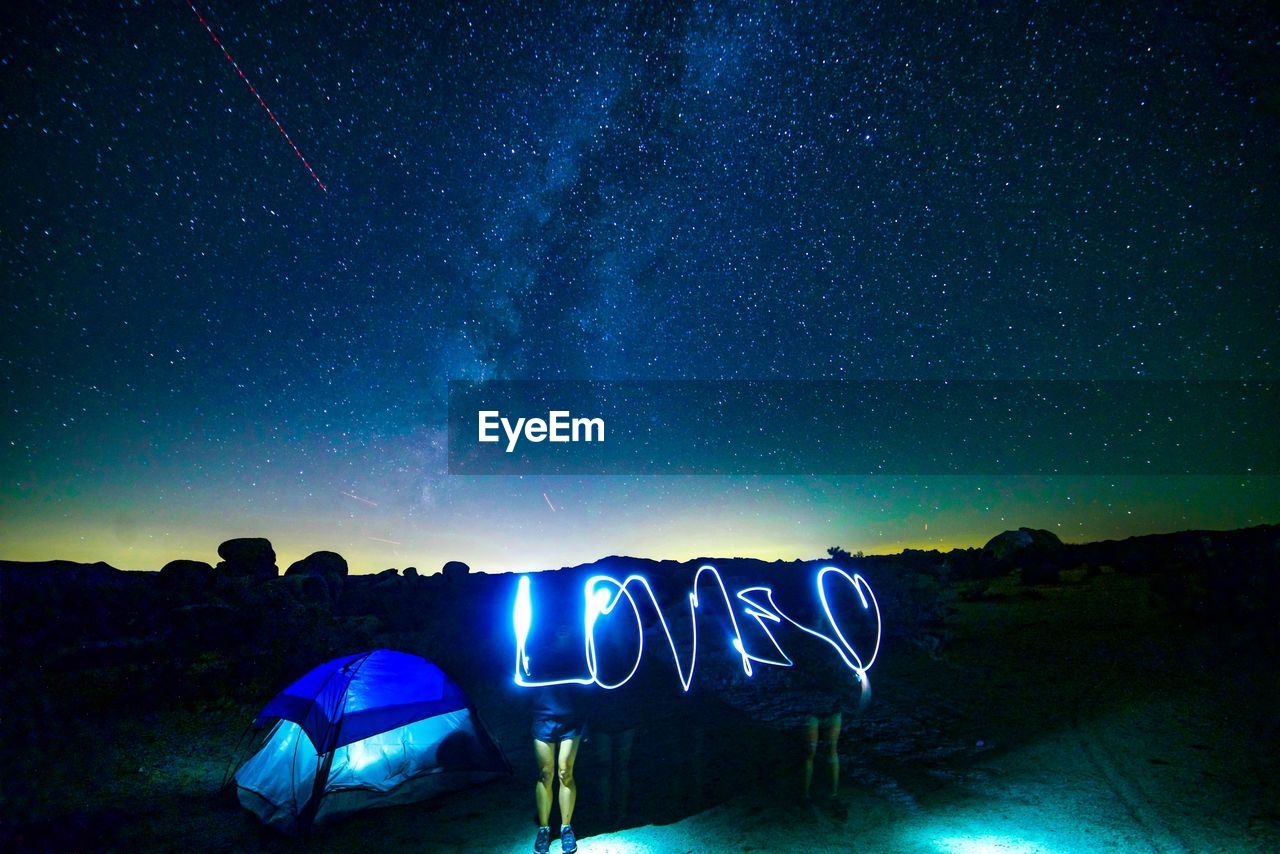 Light painting by tent against sky at night