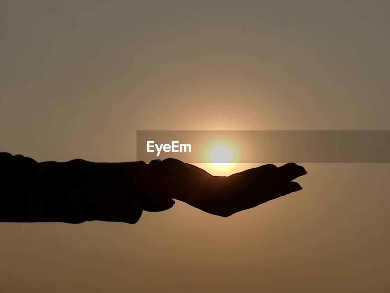 CLOSE-UP OF SILHOUETTE HAND HOLDING SUN