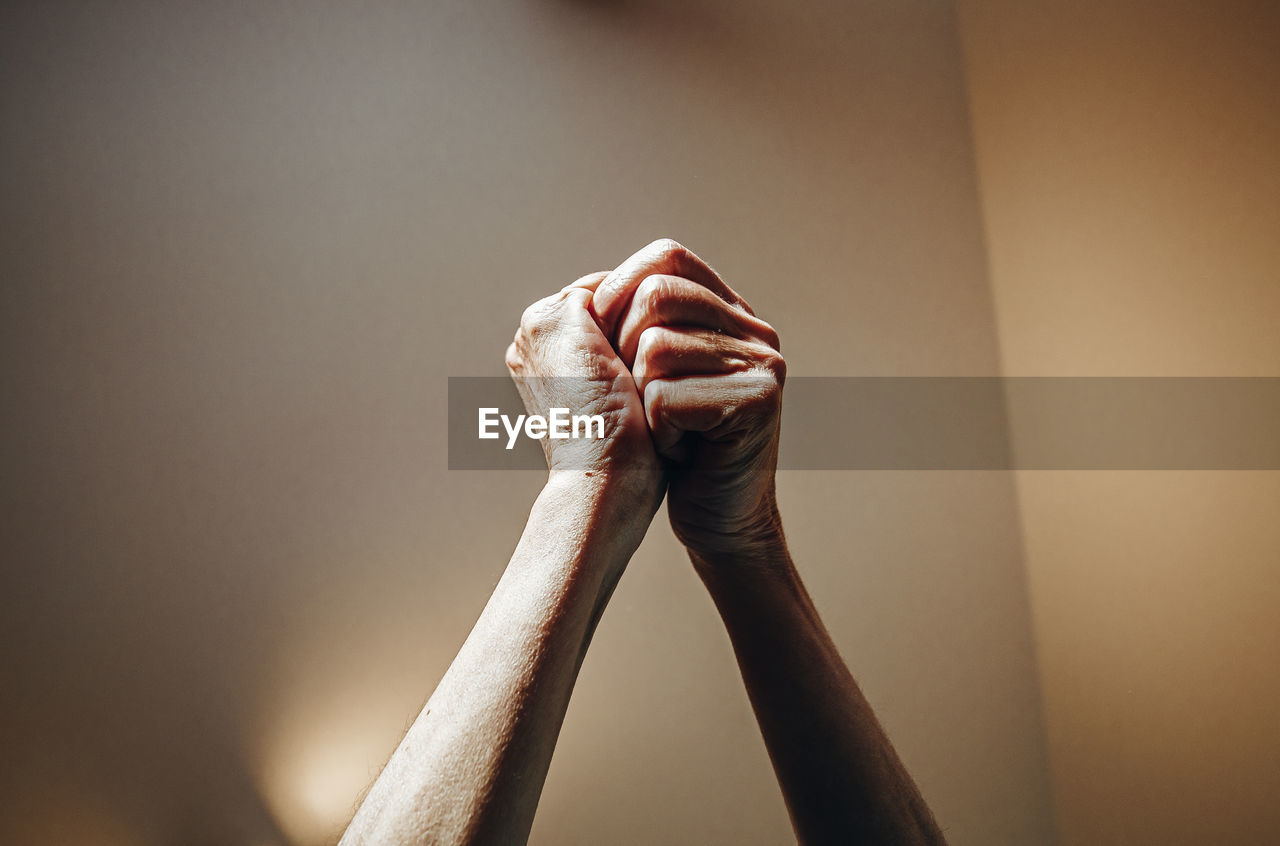 Cropped image of person holding hands against wall