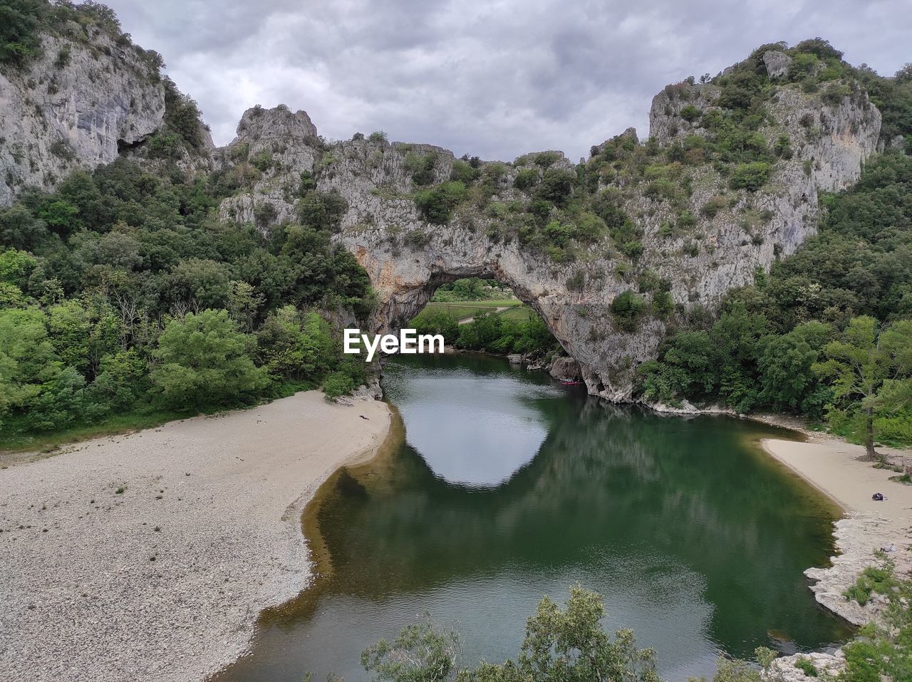 ARCH BRIDGE OVER RIVER BY TREES AGAINST SKY