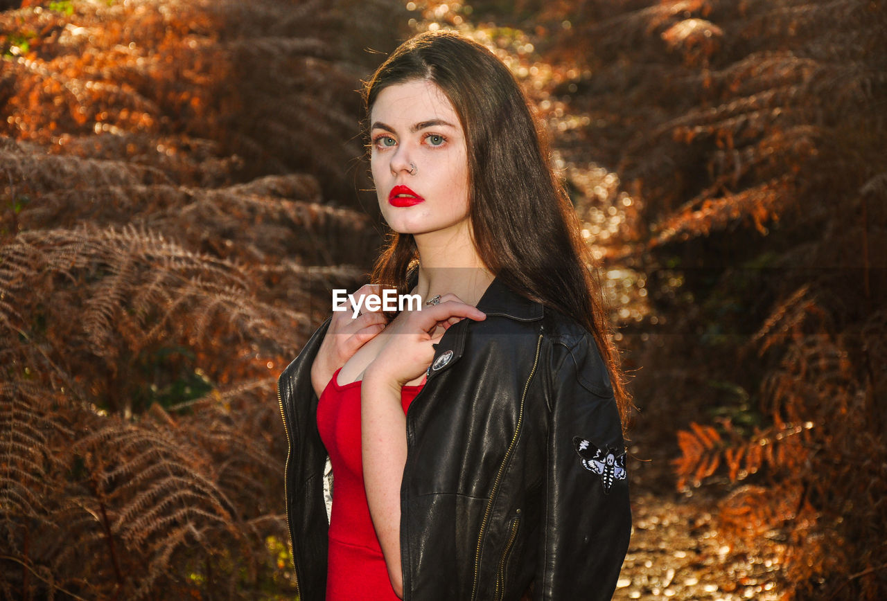 Portrait of young woman standing at forest