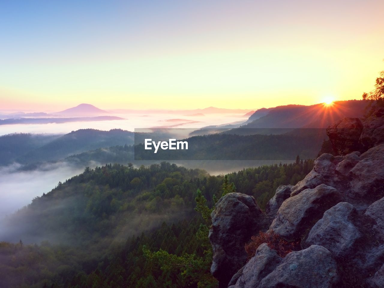 Beautiful autumnal landscape with mountain view, morning foggy valley within sunrise.