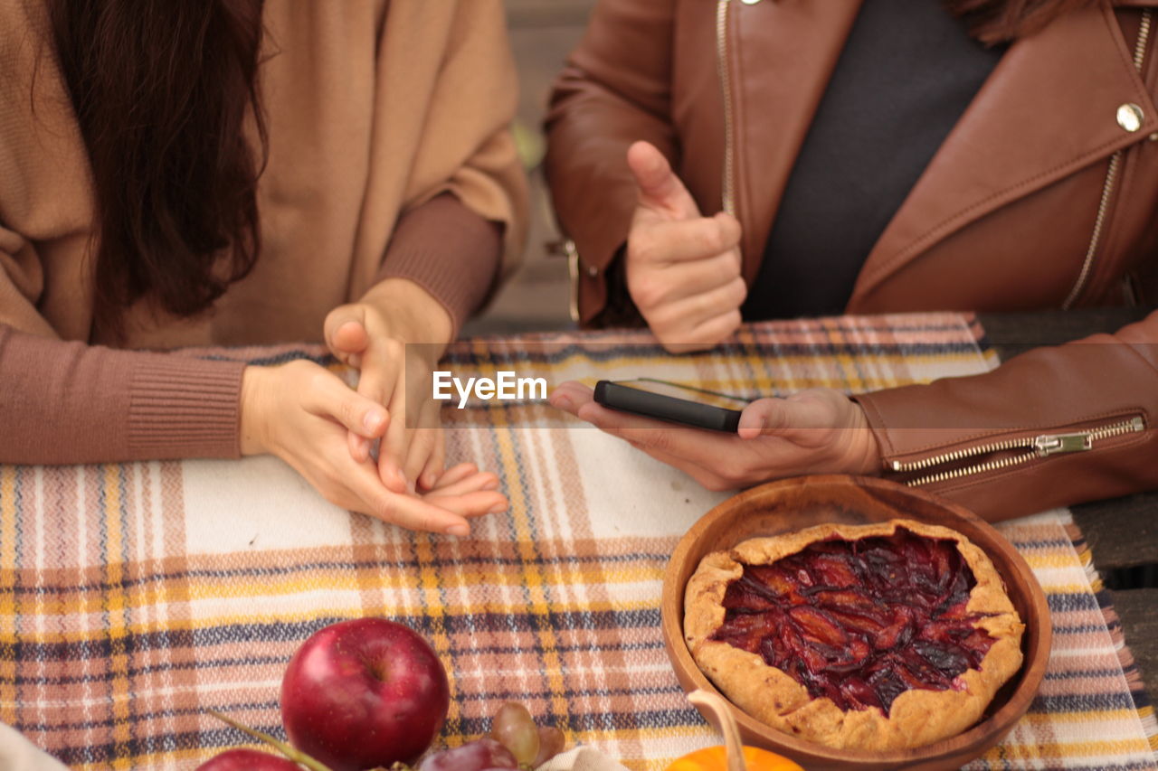 Picnic with fruits, pumpkins and pie outdoor 2 women hands