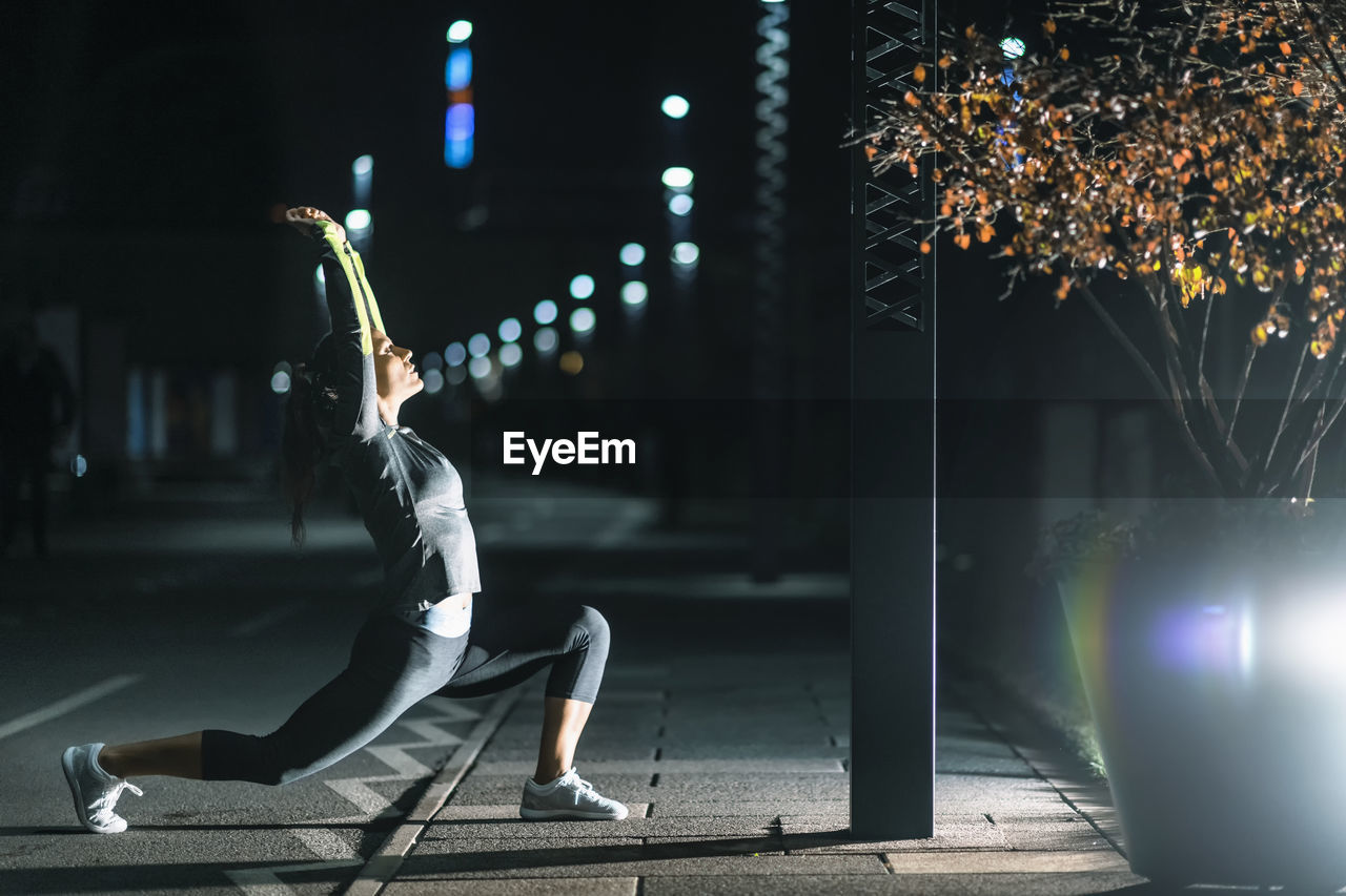 Woman exercising in city at night