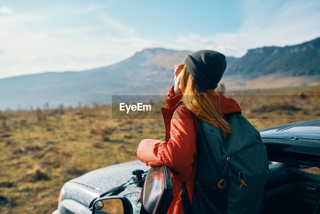 Woman looking at sunrise while standing near car