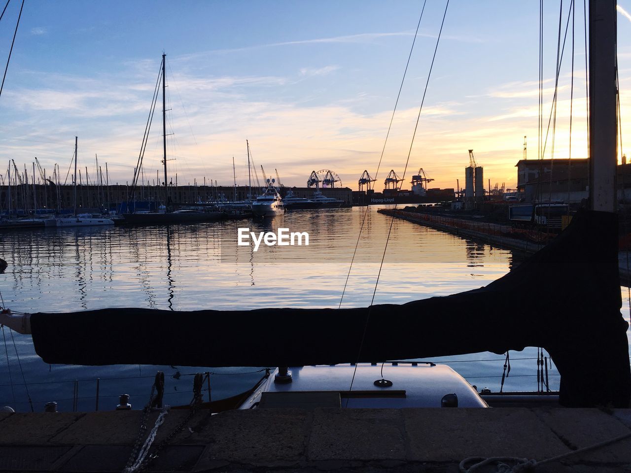 SAILBOATS MOORED IN HARBOR AT SUNSET