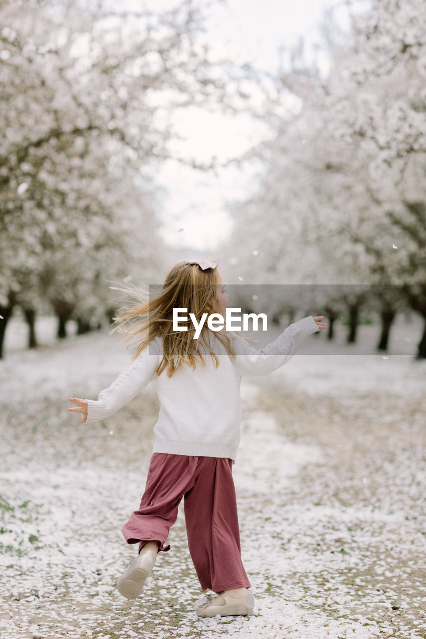 Preschool girl dancing in an almond orchard