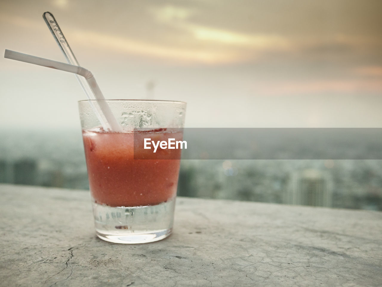 Glass of juice with the view of a city in the background