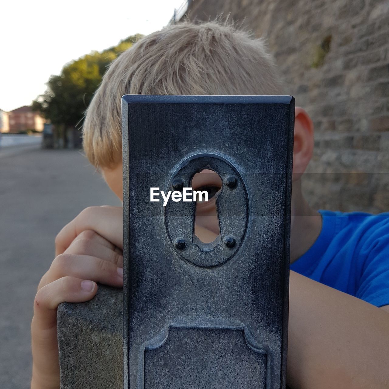 Boy looking through old keyhole against road