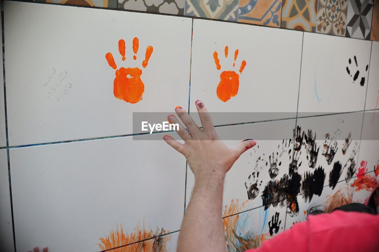 Cropped image of man with handprint on tile wall