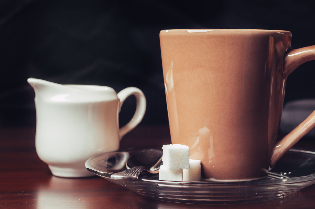 CLOSE-UP OF COFFEE CUP ON TABLE AGAINST WHITE BACKGROUND