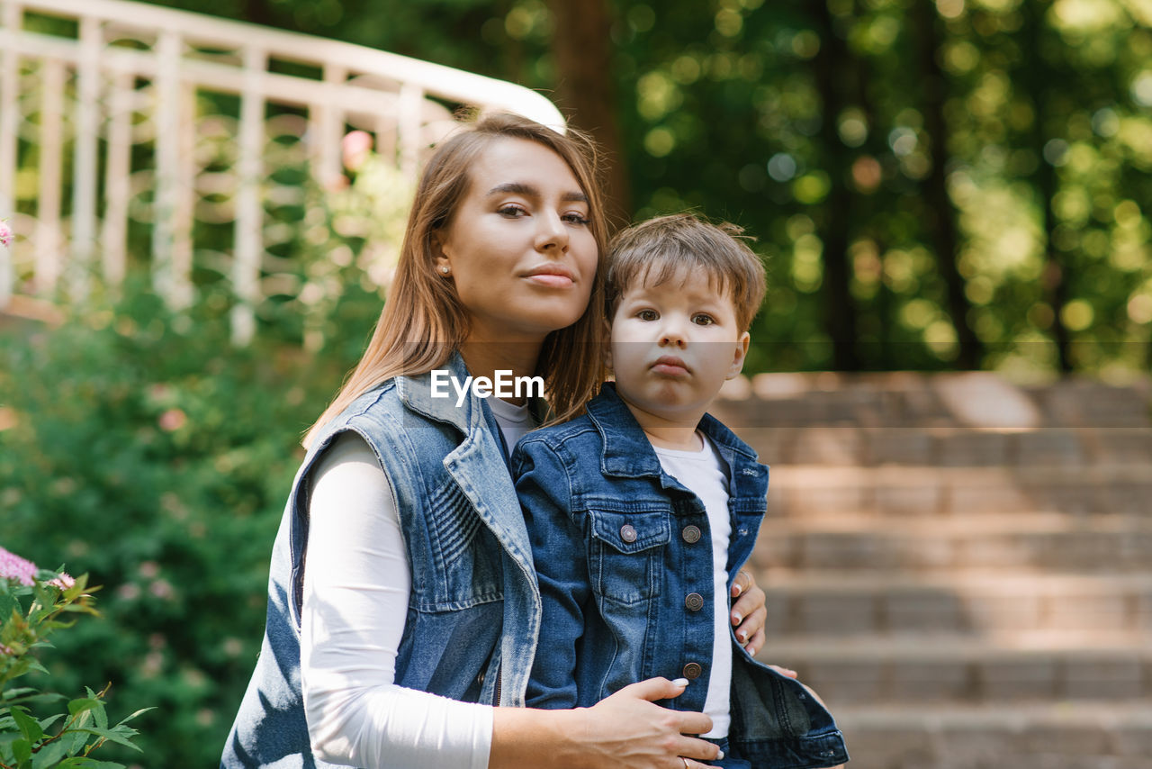 Mother with a three-year-old child playing outdoors on a sunny day in a city park