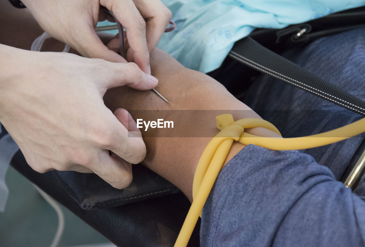 Cropped hands of doctor inserting needle on patient arm
