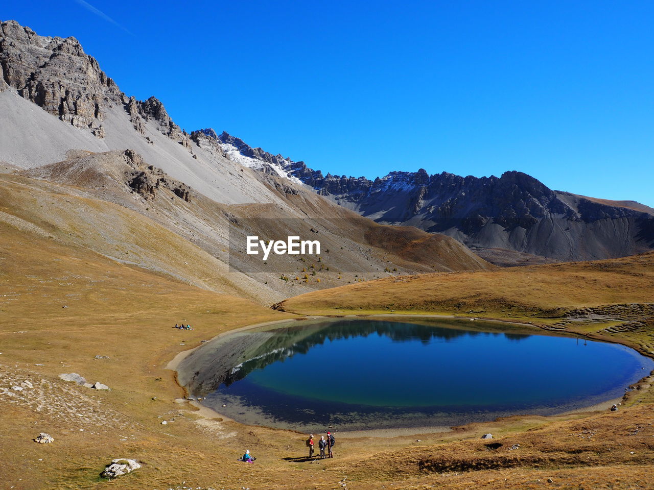 Scenic view of pond and mountains against clear blue sky