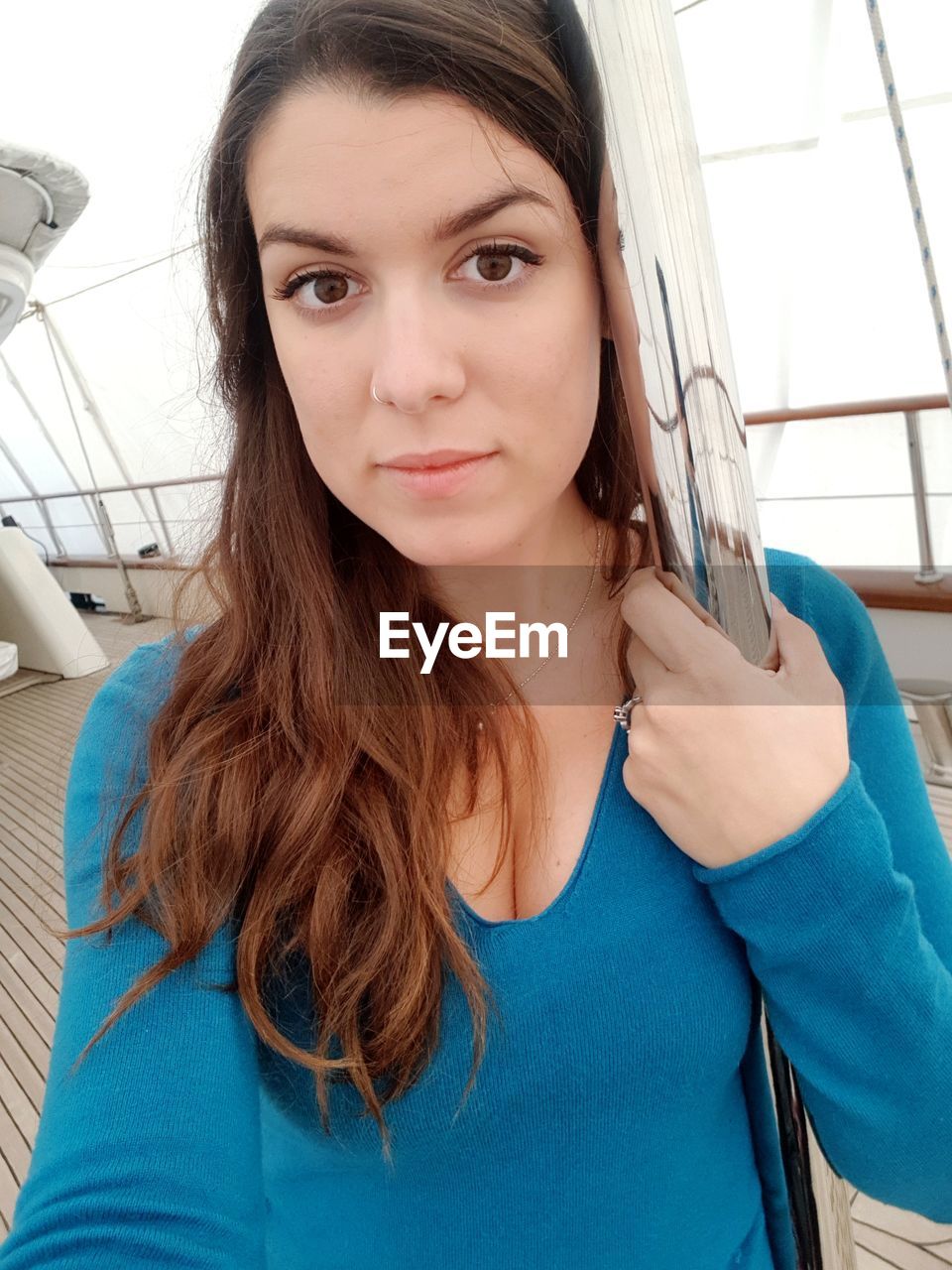 Portrait of young woman holding pole in ship