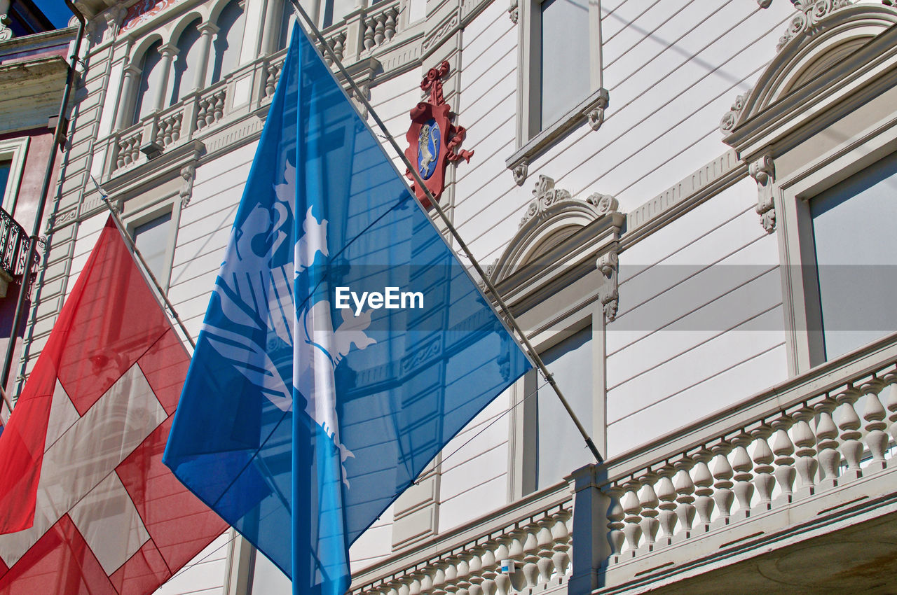 LOW ANGLE VIEW OF FLAGS AGAINST BUILDINGS