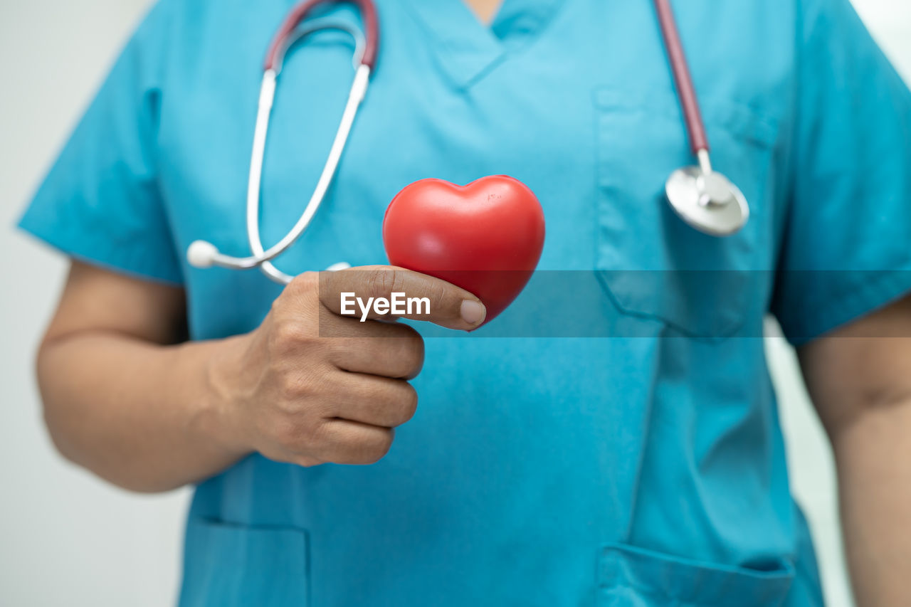 Doctor holding a red heart in hospital ward, healthy strong medical concept.