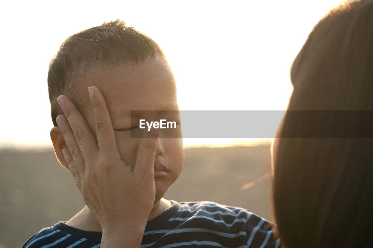 CLOSE-UP PORTRAIT OF BOY AND SON AGAINST SKY