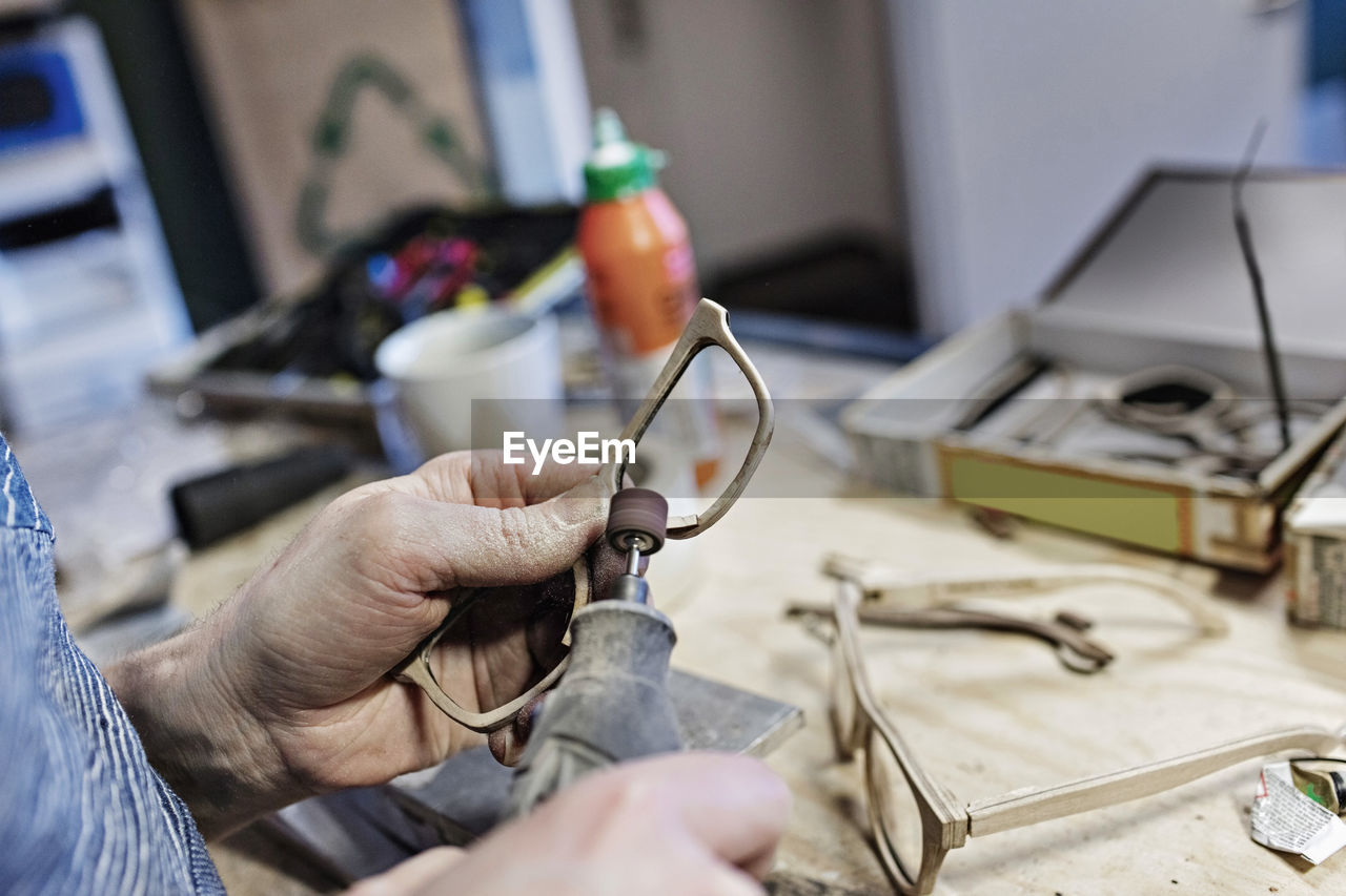 Cropped image of owner making eyeglasses with work tool at workshop