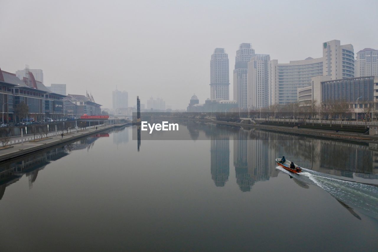 Reflection of city in lake against clear sky