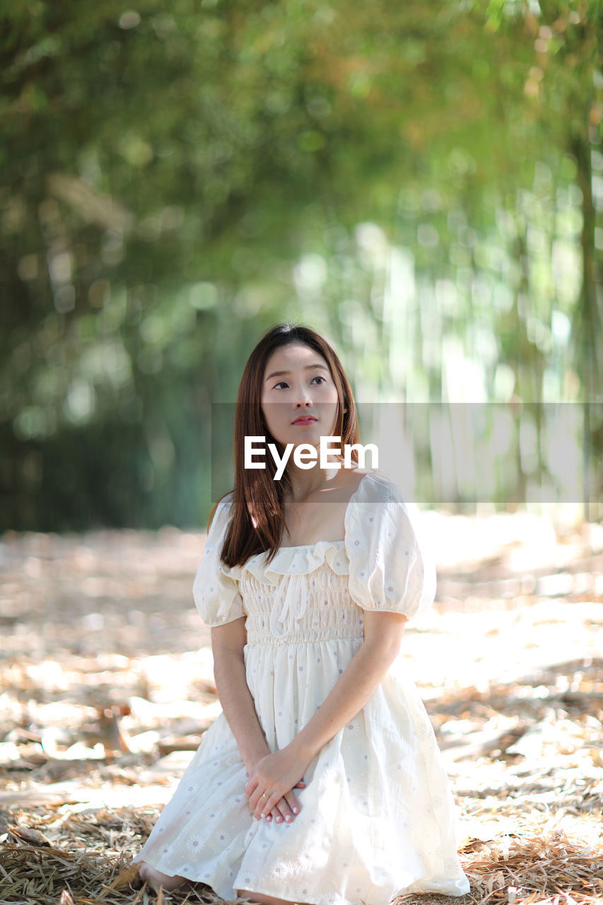 Portrait of woman sitting in park looking away