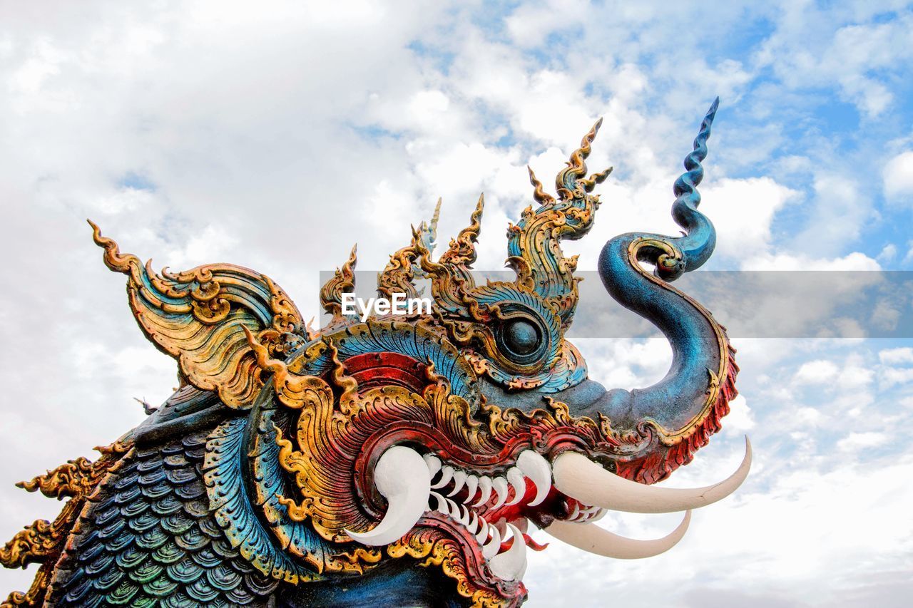 Low angle view of chinese dragon against cloudy sky