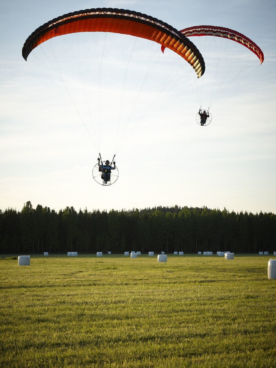 People powered paragliding over grassy field
