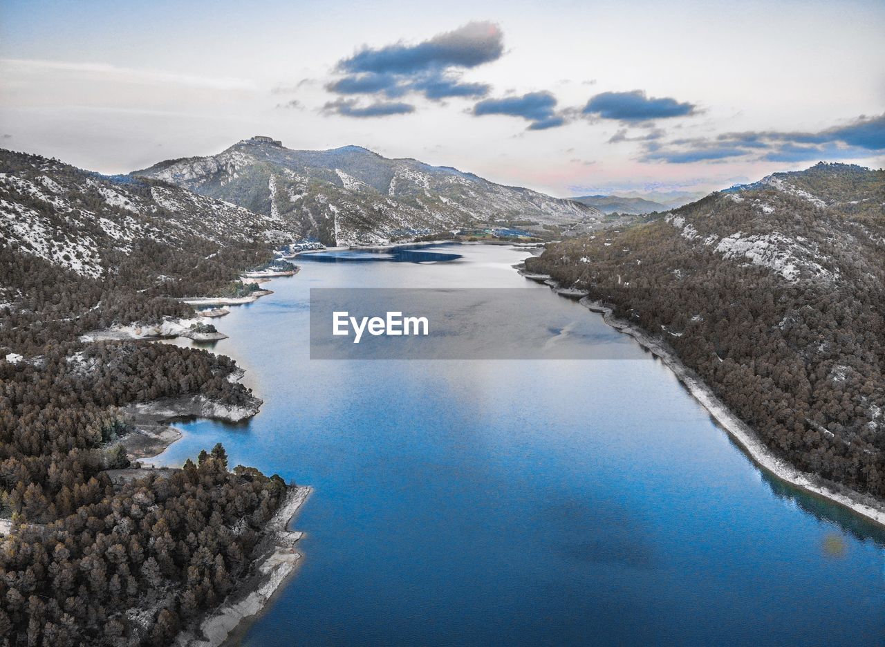 Scenic view of lake by snowcapped mountains against sky