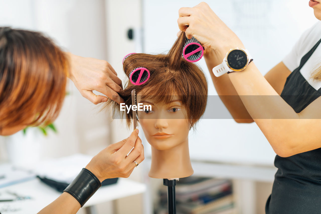 Hairstylist school - female adult student practicing how to make hair styling with hair roller